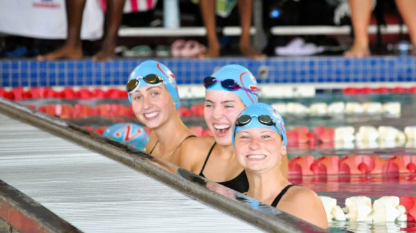 (From left to right) Evelyn Godbold (11), Anna Beauchamp (11), and Grace Styranec (11) cheering on their teammates in the Female 400 Yard Freestyle Relay.
