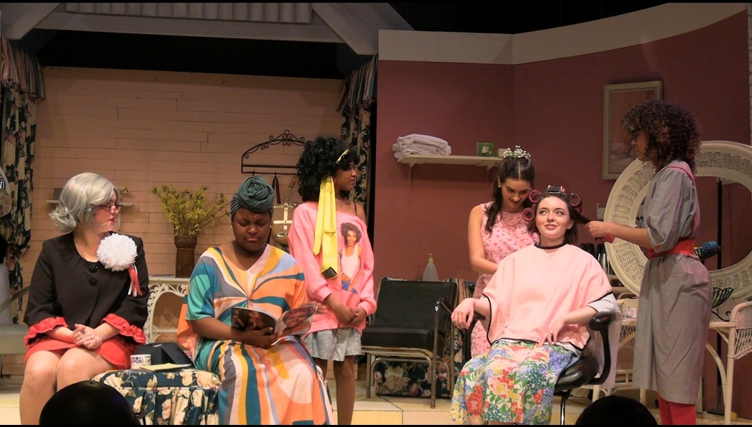 From left to right: Magnolia Charlet (12) as Clairee, Kadra Bates (12) as Ouiser, Kassidy Hall (11) as Truvy, Fiona Anderson (12) as Shelby, Kenzie Robinson (12) as MLynn, and Willia Puckett (11) gossip as MLynn gets her hair done for Shelbys wedding.