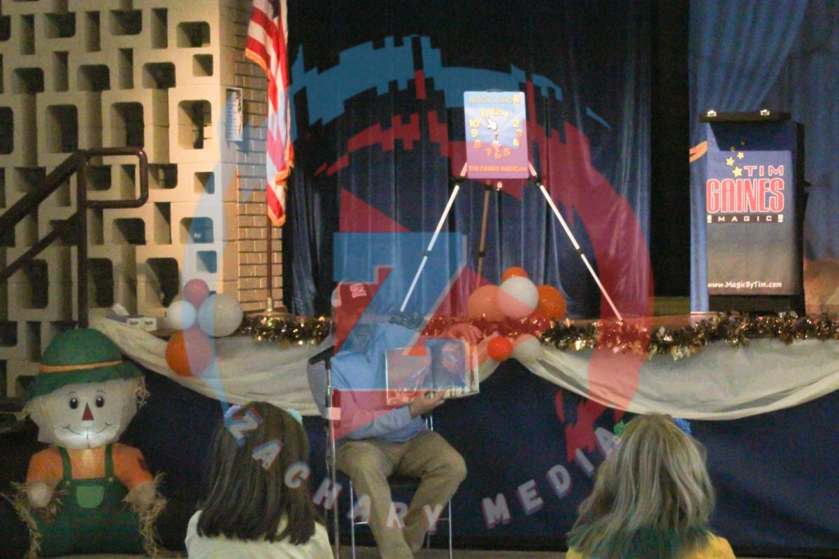 Mr. Necaise reads a book to the kids while showing them the pictures.