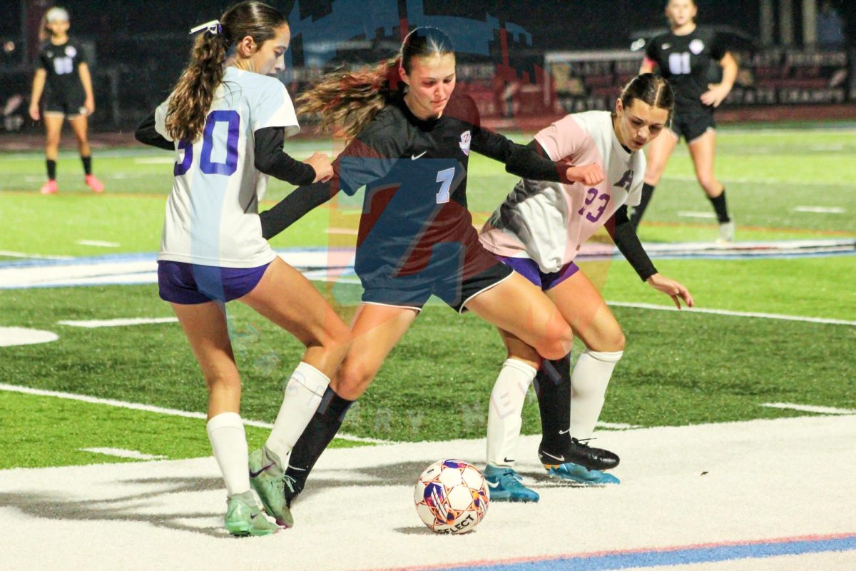 Alyssa Lillie (9) passionately double blocks two opponents from retrieving the ball.