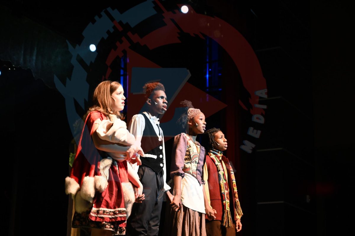 From left to right, Grace Noel (10), Da'Marion Wilson (9), Erynn Williams (10), and Tycen Smith (11) stand side by side, singing on stage.