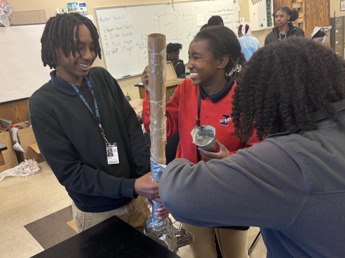 Kelan Follins (9) helps Kinomi Robins (9) finish up the tape on his team's rocket, all sharing a good laugh in the process.