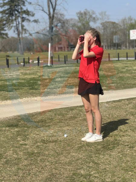 Madelyn Chatelain (11) uses her rangefinder to determine how much force the golf ball will need.