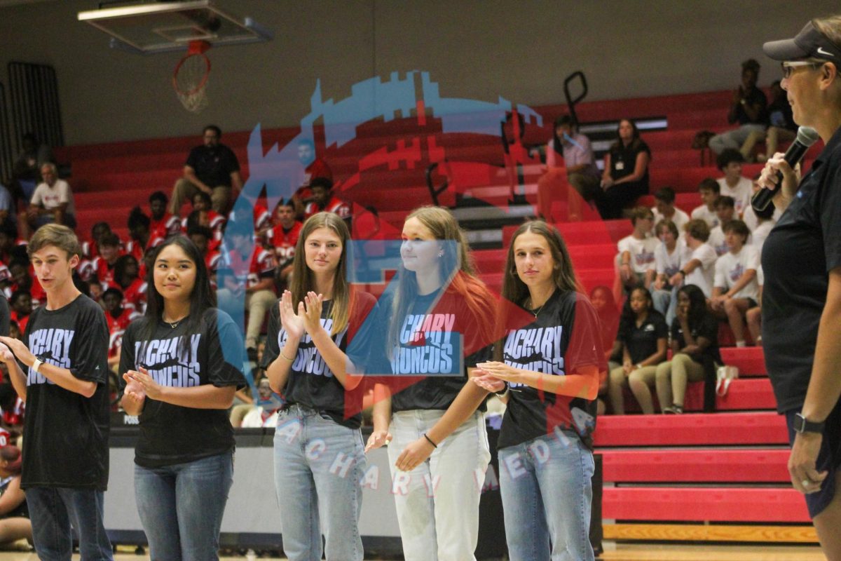 The trio of Camille Harms (12), Myra Jenkins (12), and Chloe Wedblad (12) stand next to each other during the swim teams' presentation.